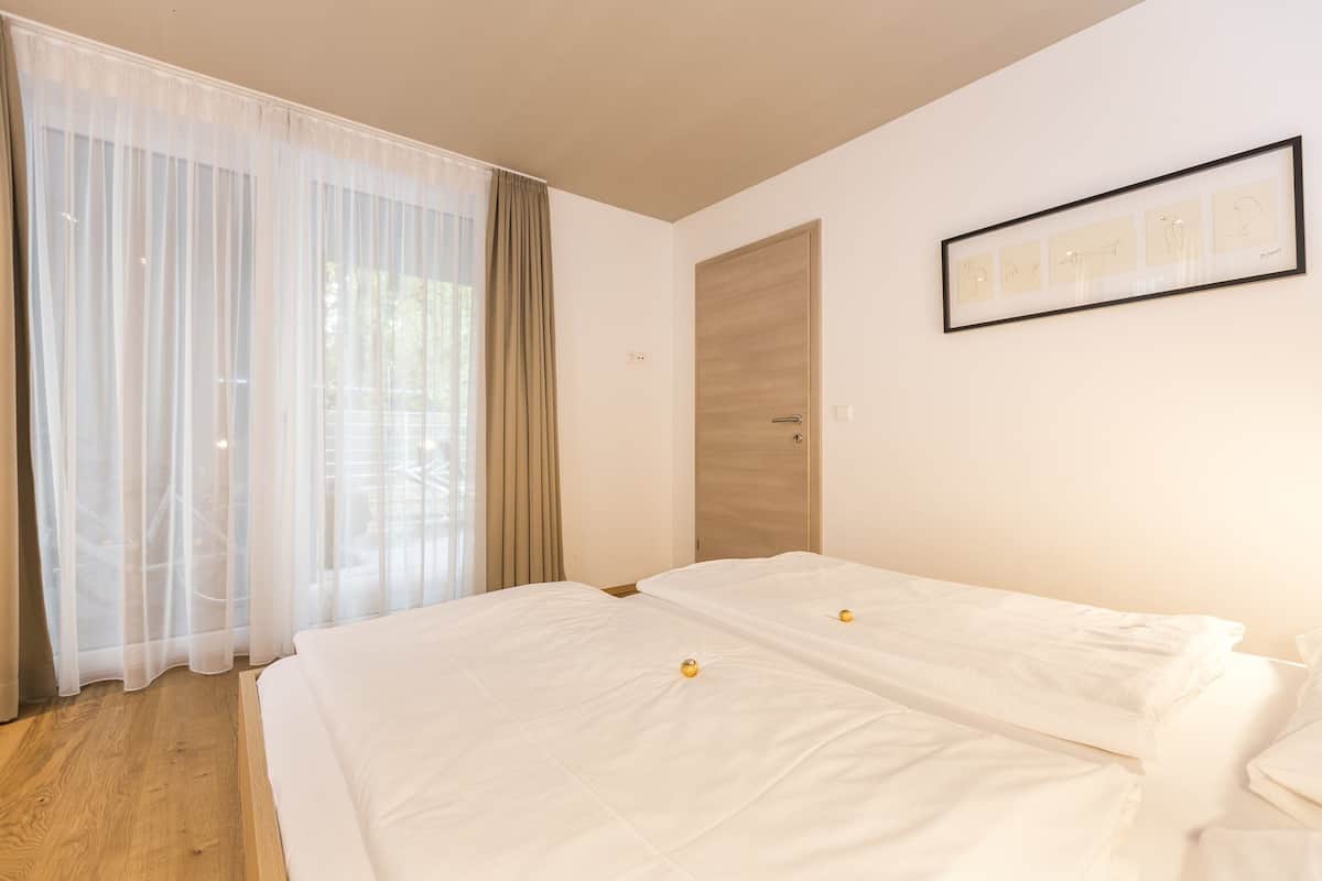 Quarto com duas camas, uma porta de madeira e um quadro na parede.