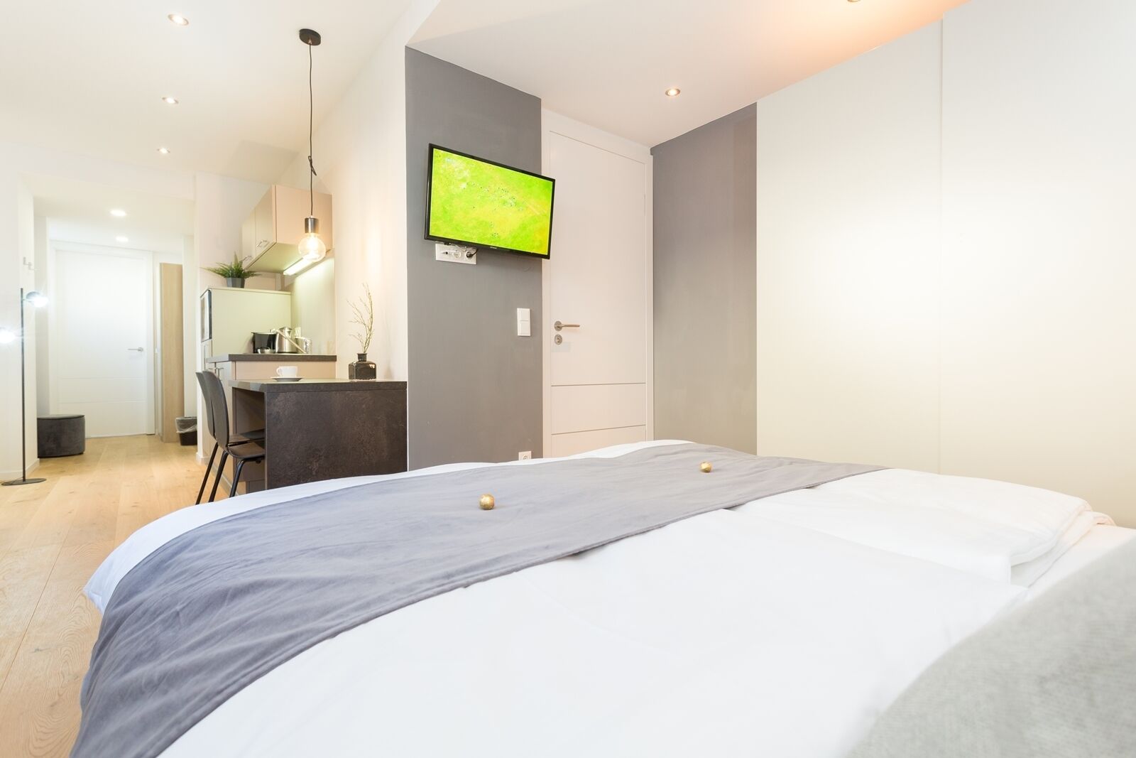 Une chambre à coucher moderne, équipée d’un lit, d’un bureau et d’une télévision.