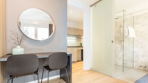 A modern kitchen with a round mirror, two chairs, and a vase on the counter. - Room 4 & 5 Apartments (Salzburg)
