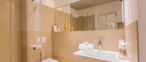 A modern bathroom with a glass shower enclosure, a white sink, and a large mirror.