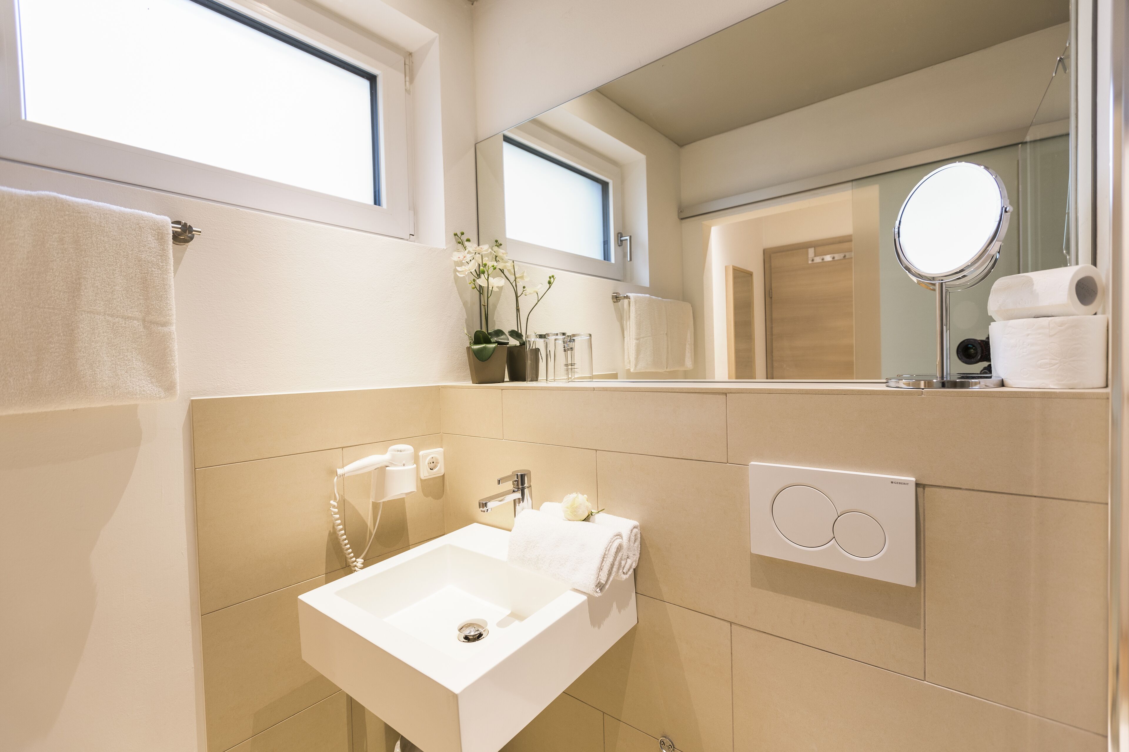 Un baño moderno con un espejo grande, un lavamanos y un perchero para toallas.