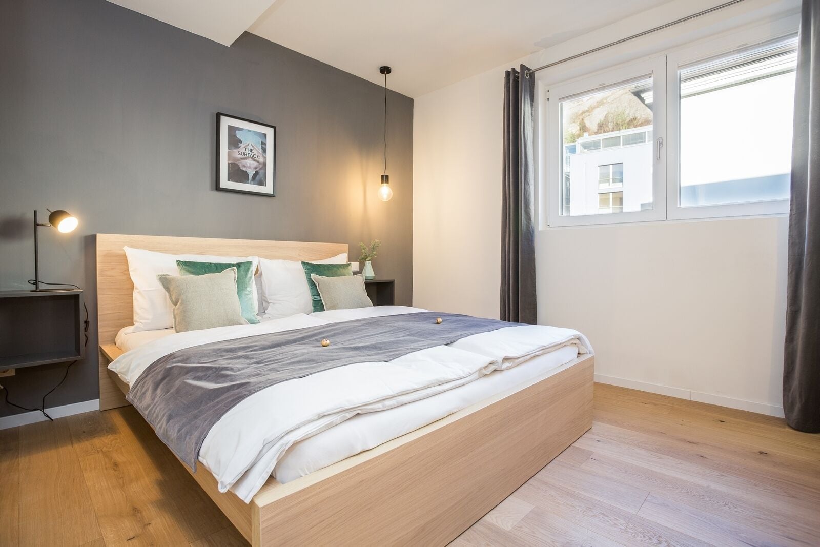 Une chambre moderne avec un lit en bois, une table de chevet, une lampe et une fenêtre avec des rideaux.
