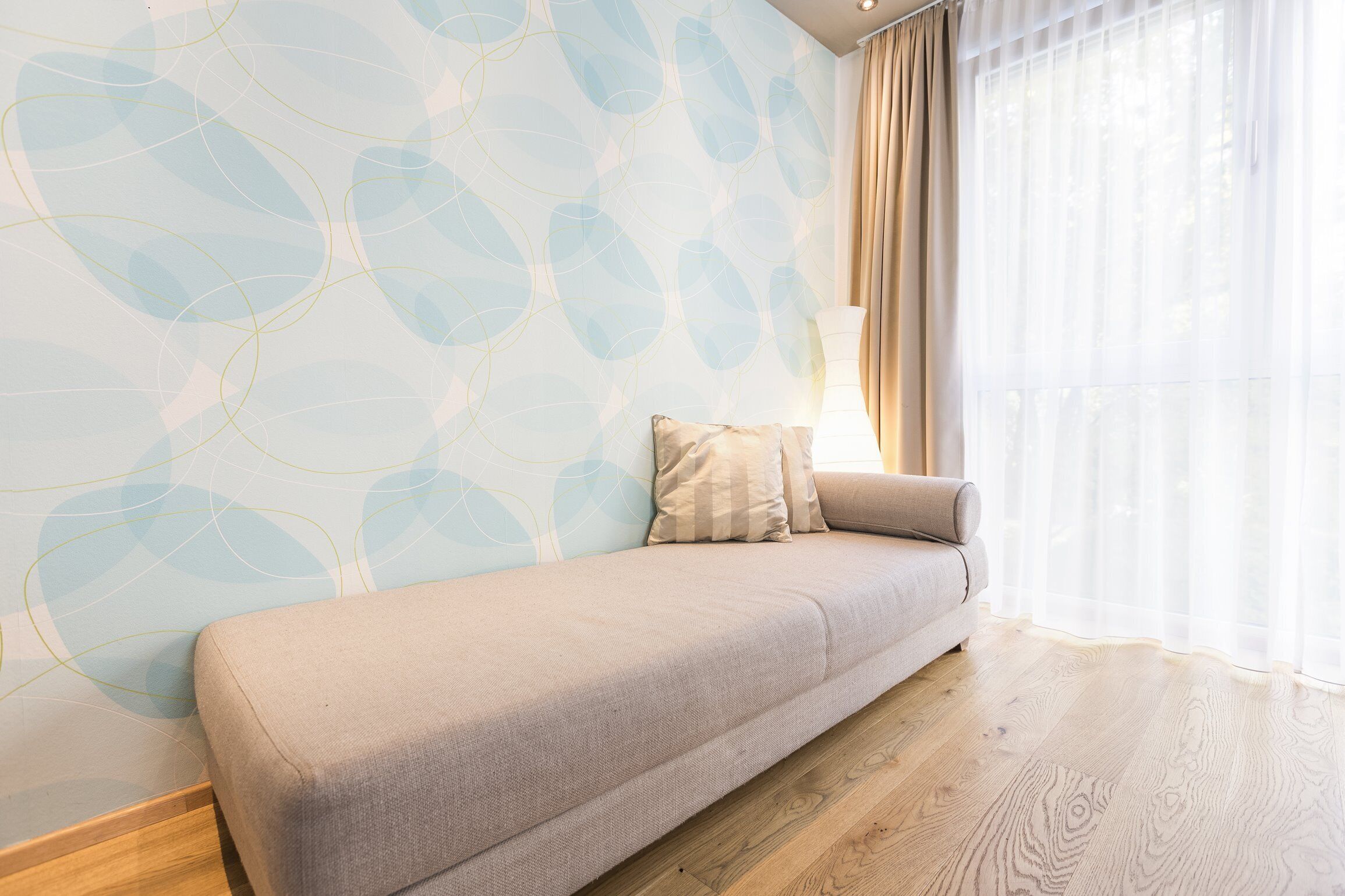 Ein modernes Wohnzimmer mit einer Couch, Holzboden und einer Wand mit Muster.