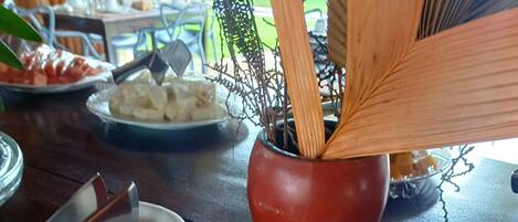 A table with a plate of croissants and a red bowl with a spoon.