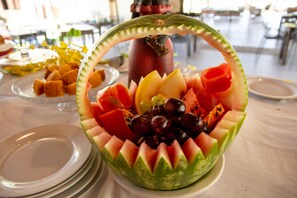 Een decoratieve schaal met een fruitschaal, onder andere met watermeloen, meloen en druiven.