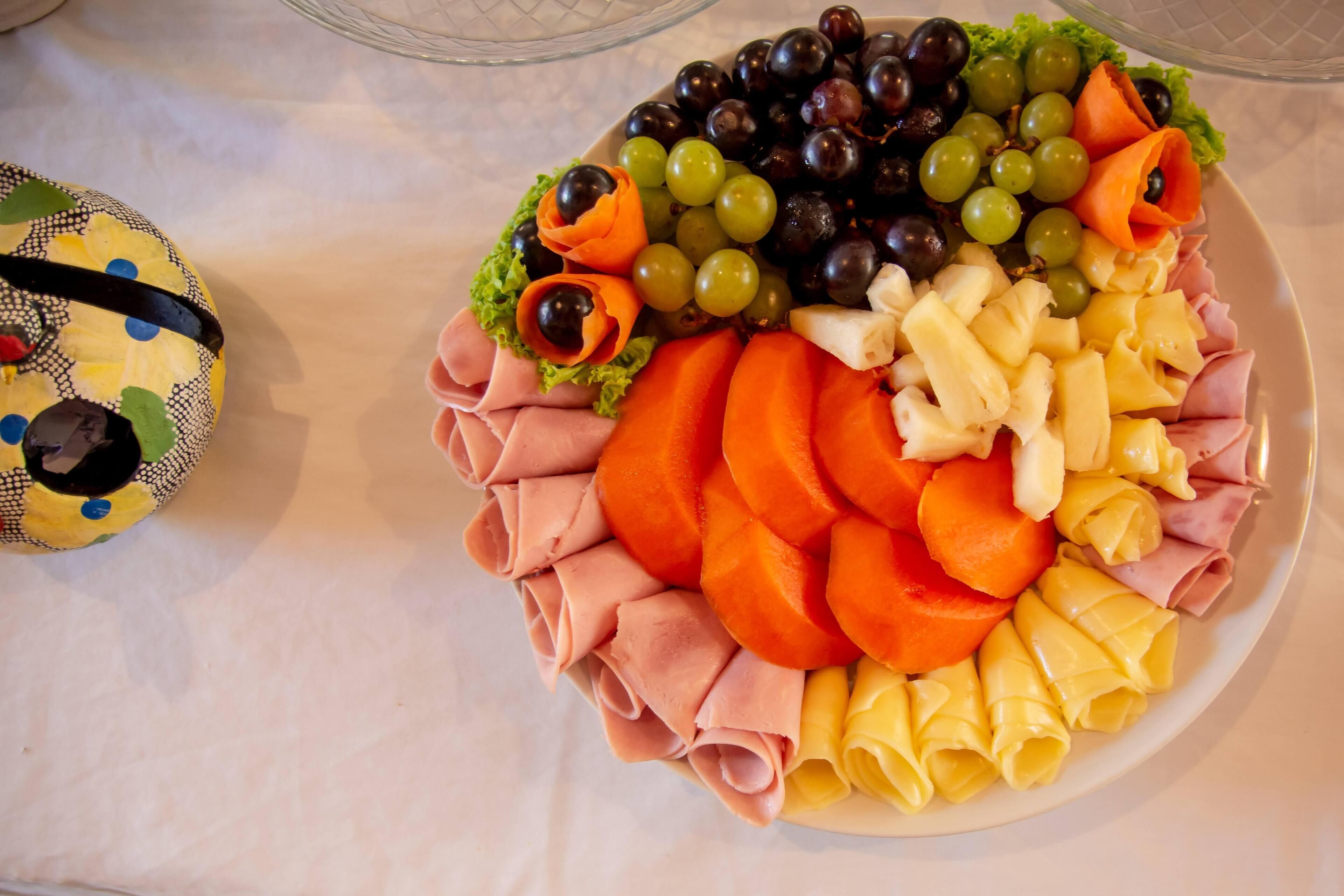 A round platter with various food items including grapes, carrots, and cheese.