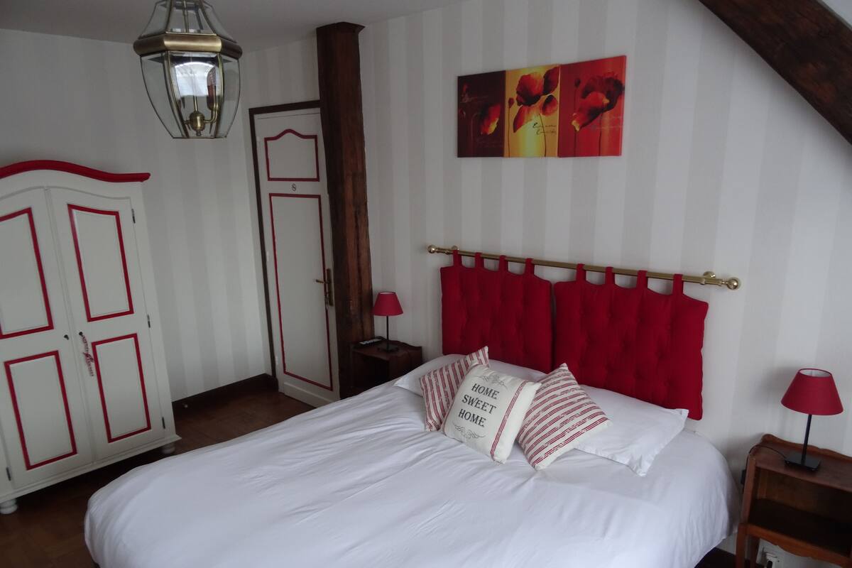 Ein Schlafzimmer mit Bett, Kleiderschrank, Tür, Lampe und einem Bild an der Wand.