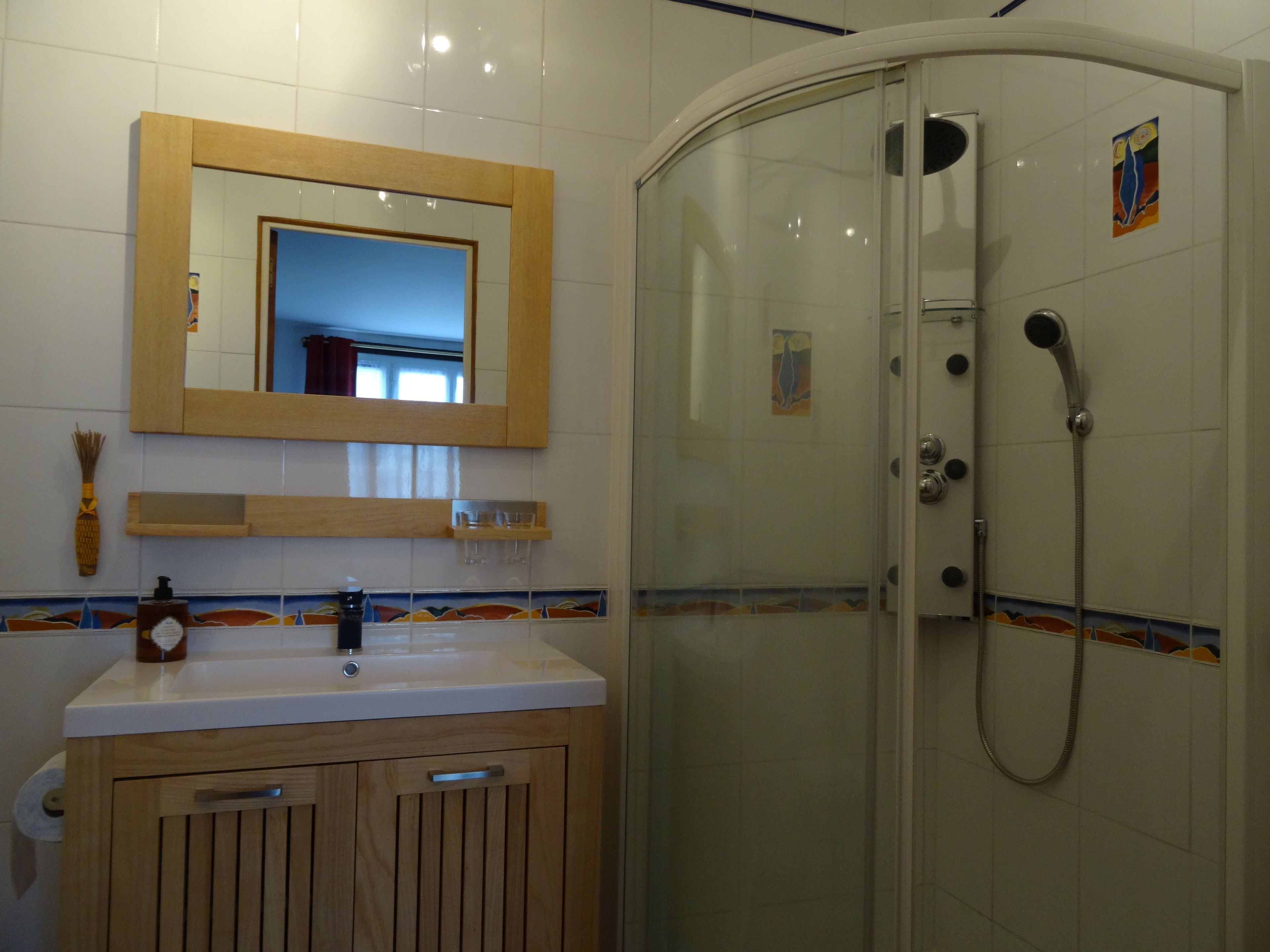 A bathroom with a glass-enclosed shower, a wooden vanity, a mirror, and a tiled backsplash.