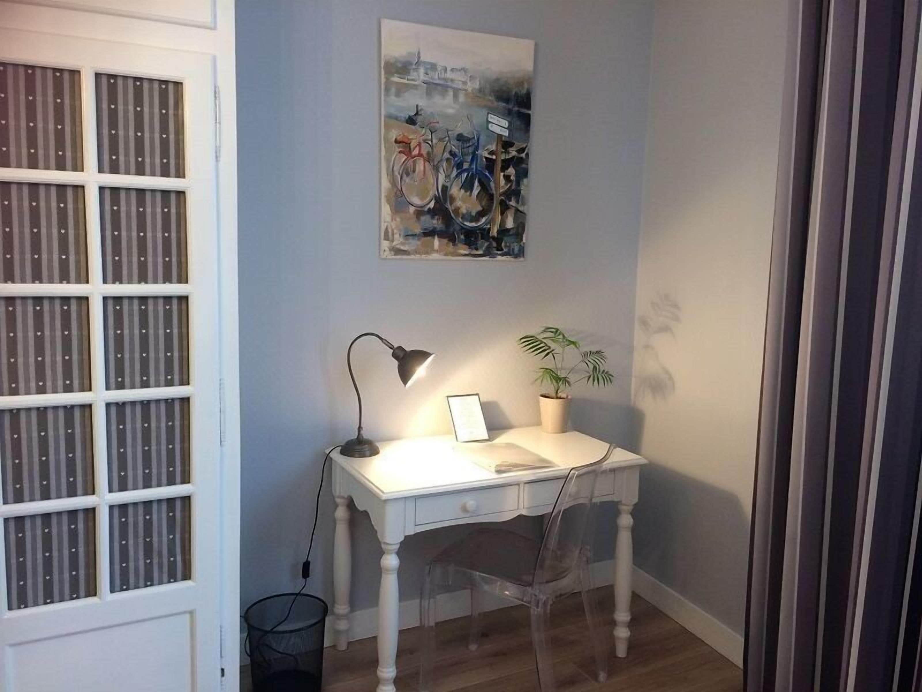 Un petit bureau comprenant un bureau, une chaise, une lampe et une plante en pot.
