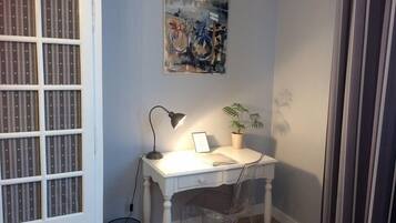 Un petit bureau comprenant un bureau, une chaise, une lampe et une plante en pot.