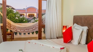 A hotel room with a bed, a view of the garden, and a balcony. - Hotel Villa Beija Flor (Jijoca de Jericoacoara)