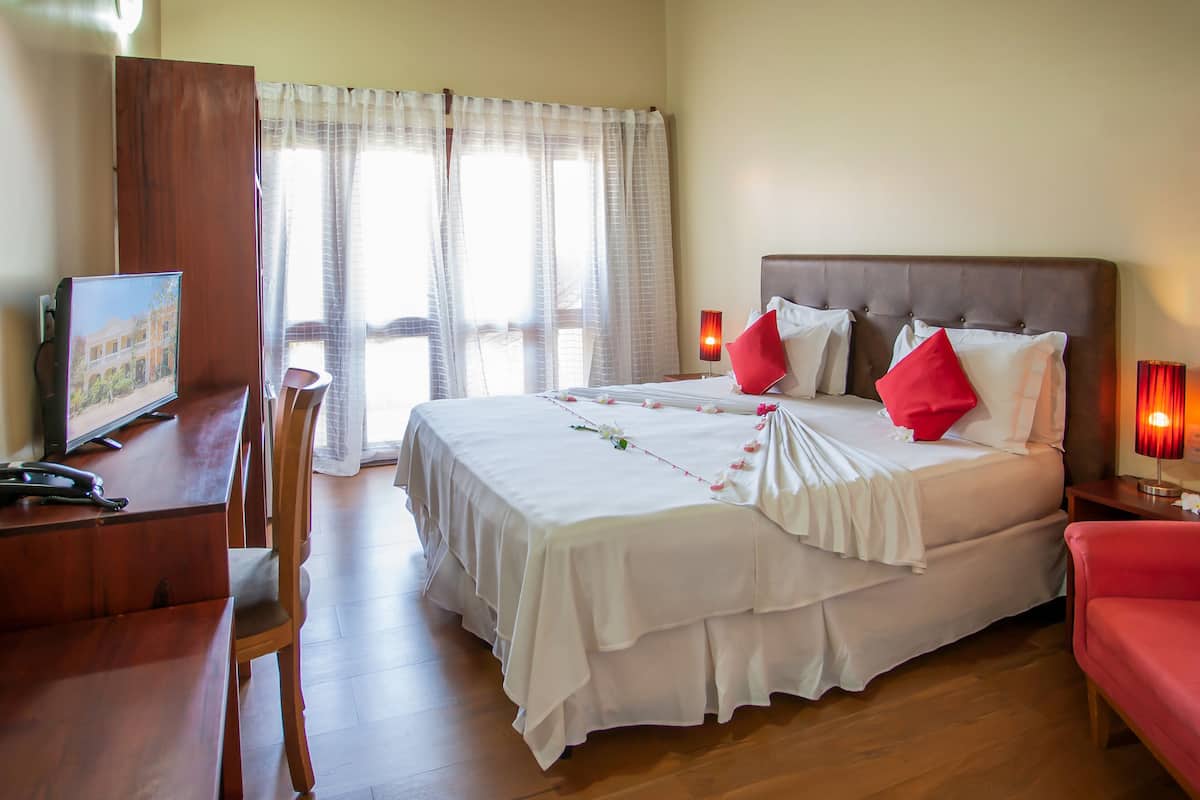 Une chambre d’hôtel avec un grand lit, un bureau avec un ordinateur et une chaise.