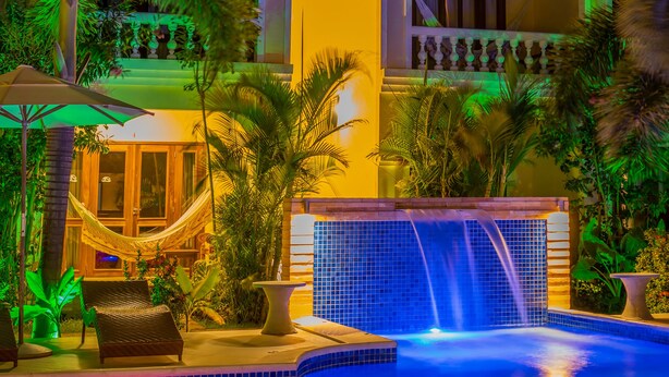 A nighttime view of a resort with a swimming pool, palm trees, and a building with a moonlit sky. - Hotel Villa Beija Flor (Jijoca de Jericoacoara)