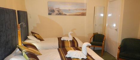 Une chambre d’hôtel avec deux lits, un tableau au mur, une chaise et une porte.