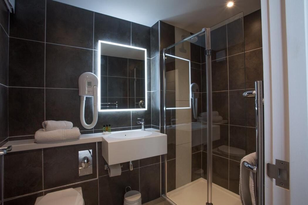 Un bagno moderno con doccia vetrata, lavandino bianco e uno specchio grande.