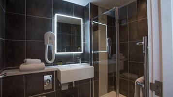 Un bagno moderno con doccia vetrata, lavandino bianco e uno specchio grande.