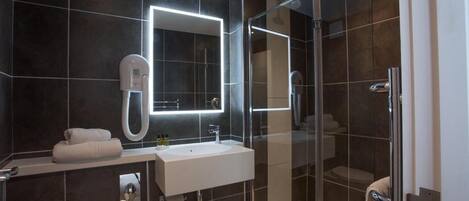 A modern bathroom with a glass-enclosed shower, a white sink, and a large mirror.