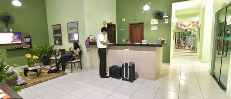 A reception area with a counter, chairs, a television, and a potted plant.