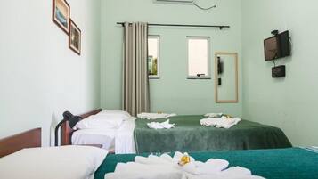 A hotel room with two beds, a window with curtains, a mounted TV, and an air conditioning unit.