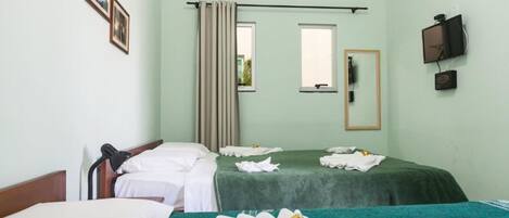 A hotel room with two beds, a window with curtains, a mounted TV, and an air conditioning unit.