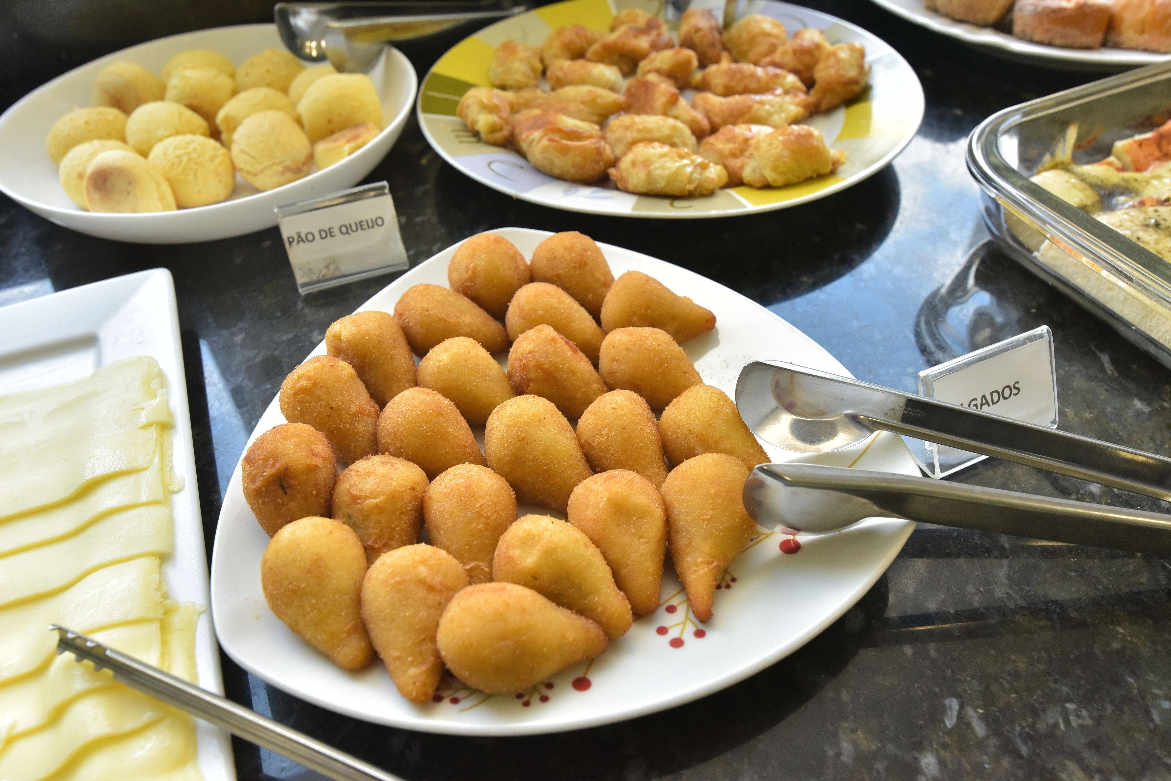 Un bufé con diversos platos, incluyendo una bandeja de frituras doradas, una bandeja de esferas amarillas y una bandeja de pasteles.