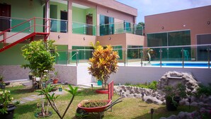 Un edificio moderno con piscina, plantas exteriores y una escalera roja.
