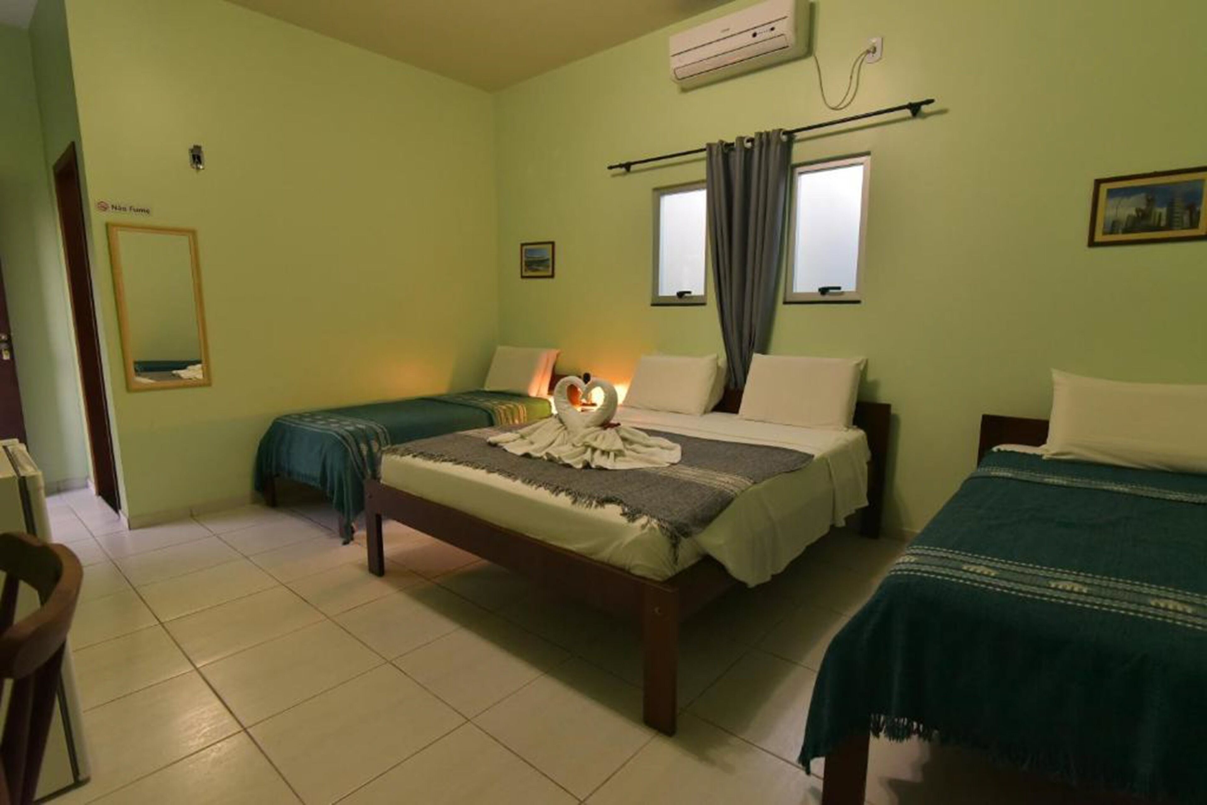 A room with two beds, a mirror, and an air conditioning unit.