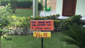 A sign in front of a building with a green door and a small garden.