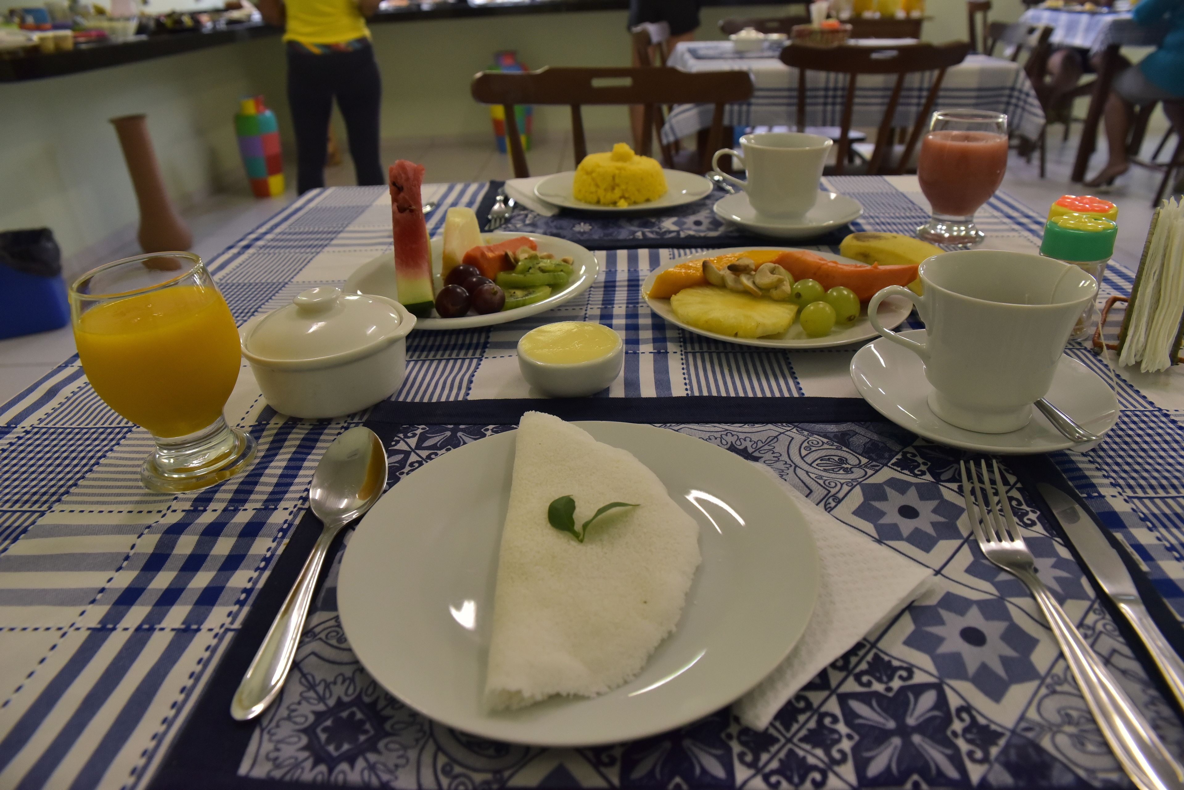 Une table de petit-déjeuner avec des assiettes remplies de nourriture, un verre de jus d’orange et une tasse de café.