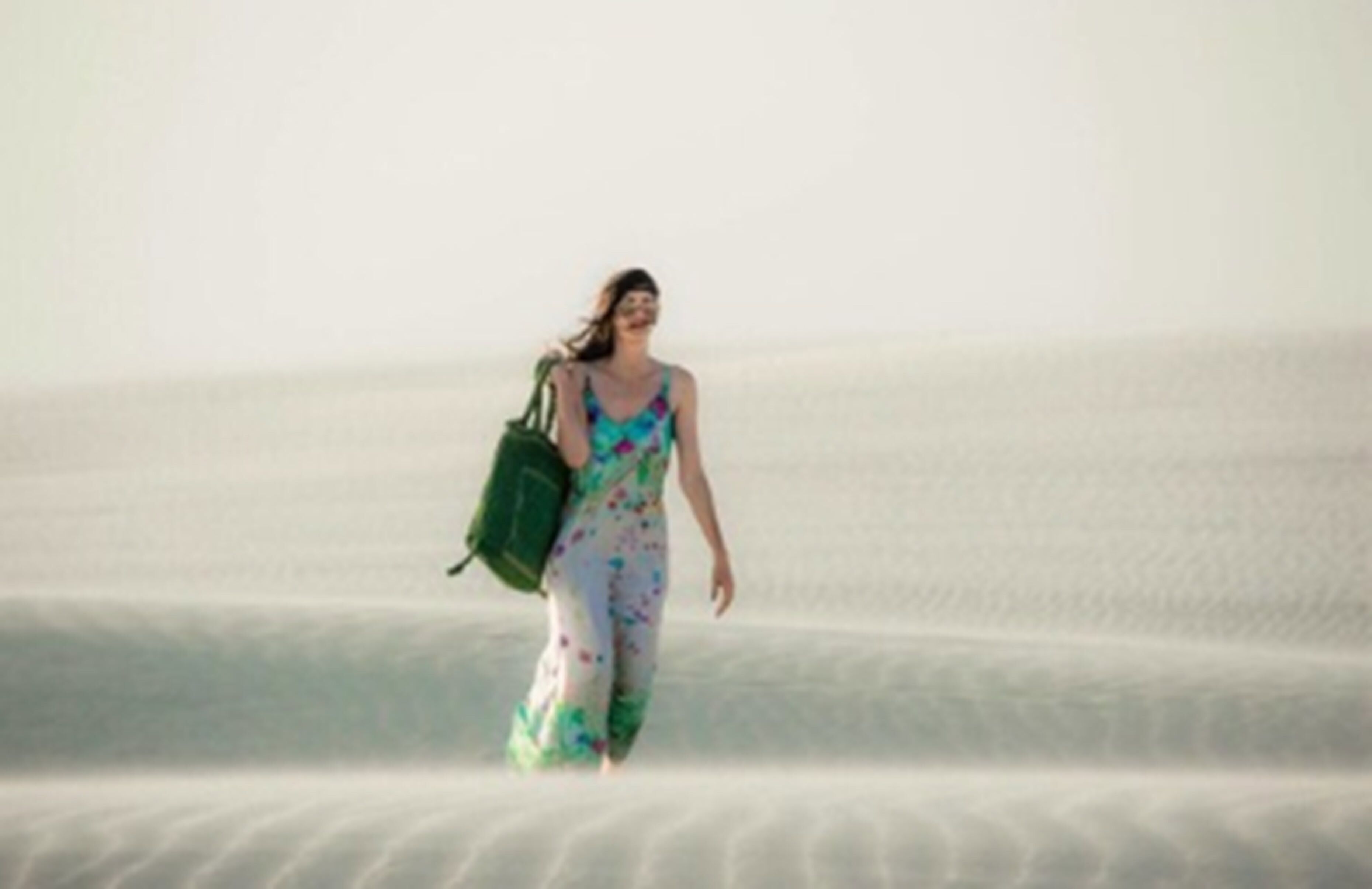 Una persona caminando sobre una playa arenosa.