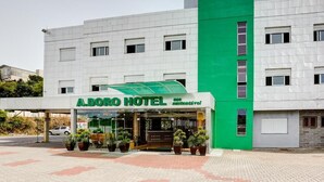 A hotel with a green and white facade, a covered entrance, and potted plants in front. - Adoro Hotel (Farroupilha)
