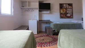 A bedroom with a bed, a desk, a TV, and a wardrobe.