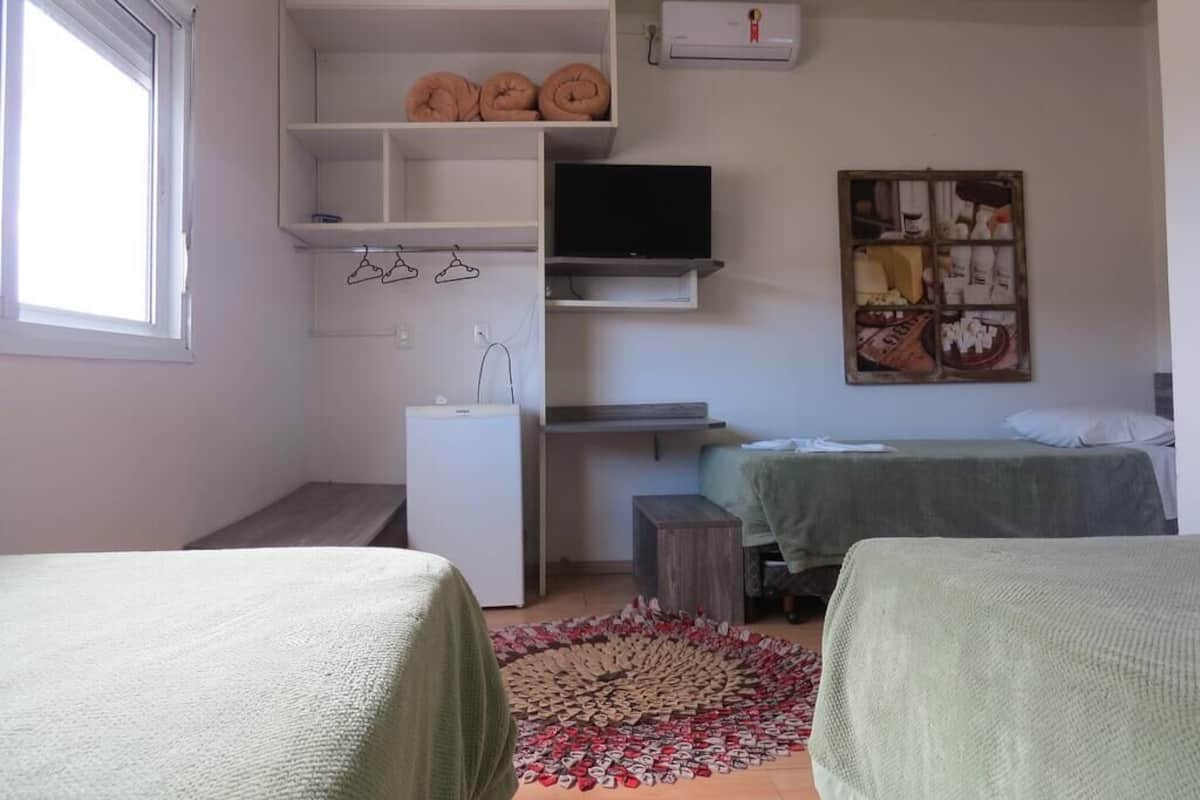 A bedroom with a bed, a desk, a TV, and a wardrobe.