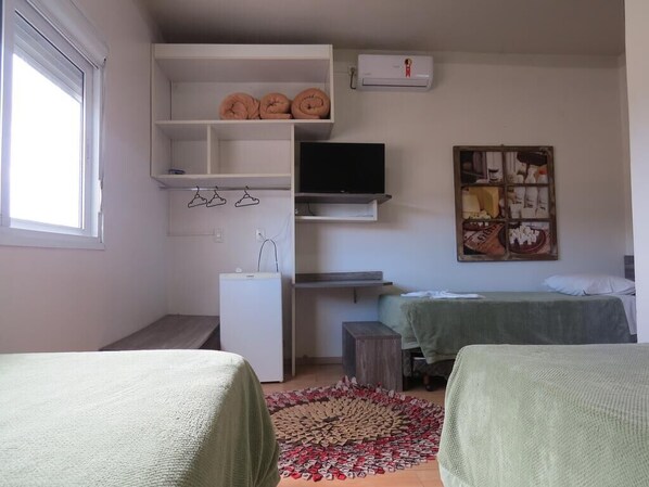 Un dormitorio con cama, escritorio, televisor y armario.