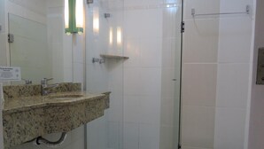 A bathroom with a glass-enclosed shower, a white toilet, and a granite countertop sink.