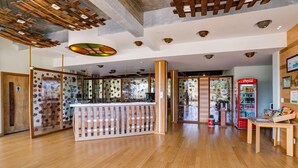 A spacious lobby with wooden flooring, a central reception desk, and a Coca-Cola vending machine. - Adoro Hotel (Farroupilha)