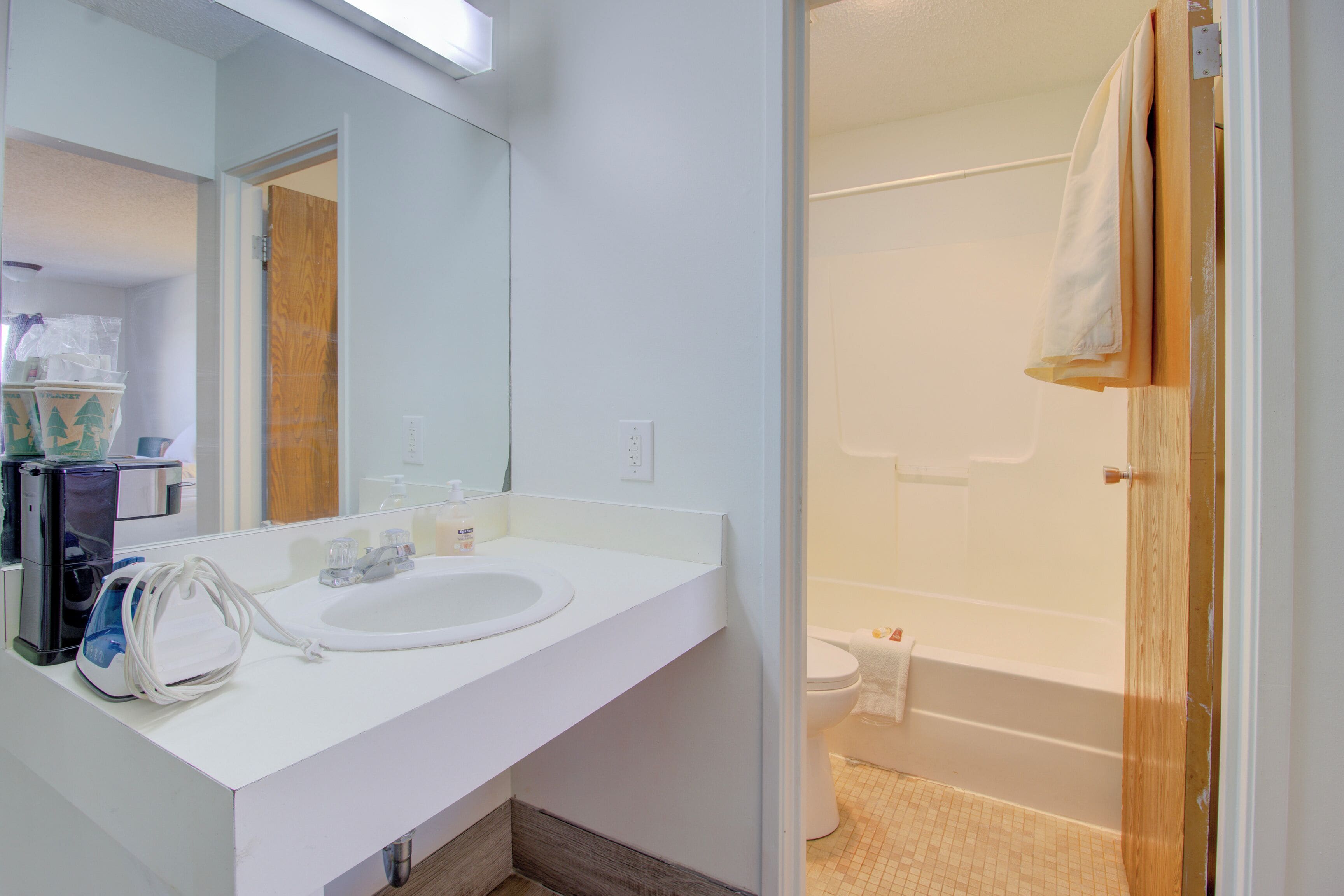 A bathroom with a white sink, mirror, and a shower area.