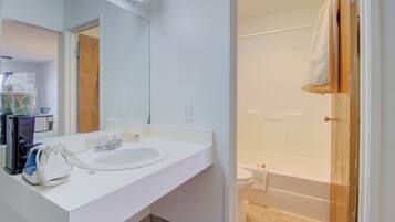 A bathroom with a white sink, mirror, and a shower area.