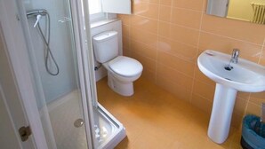 A bathroom with a glass shower enclosure, a toilet, and a sink. - Hostal Ávila (Zaragoza)