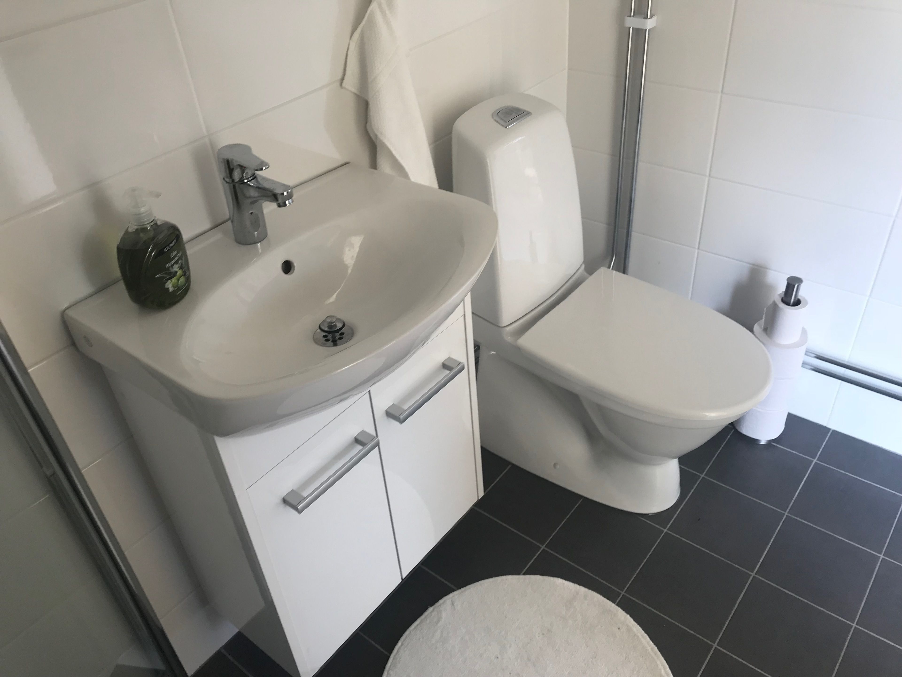 Un baño con lavamanos, inodoro y ducha blancos.