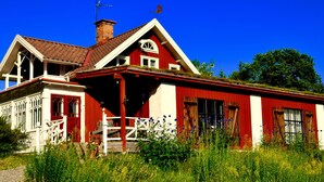 Una casa roja y blanca con porche, ventanas grandes y chimenea.