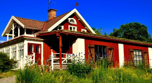 A red and white house with a porch, large windows, and a chimney.