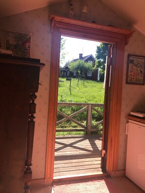 A room with a wooden door leading to an outdoor wooden deck.