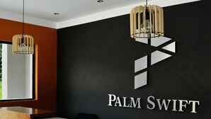 A reception desk with a black wall and a logo that reads "PALM SWIFT". - Palm Swift Luxury Accommodation (Brits)