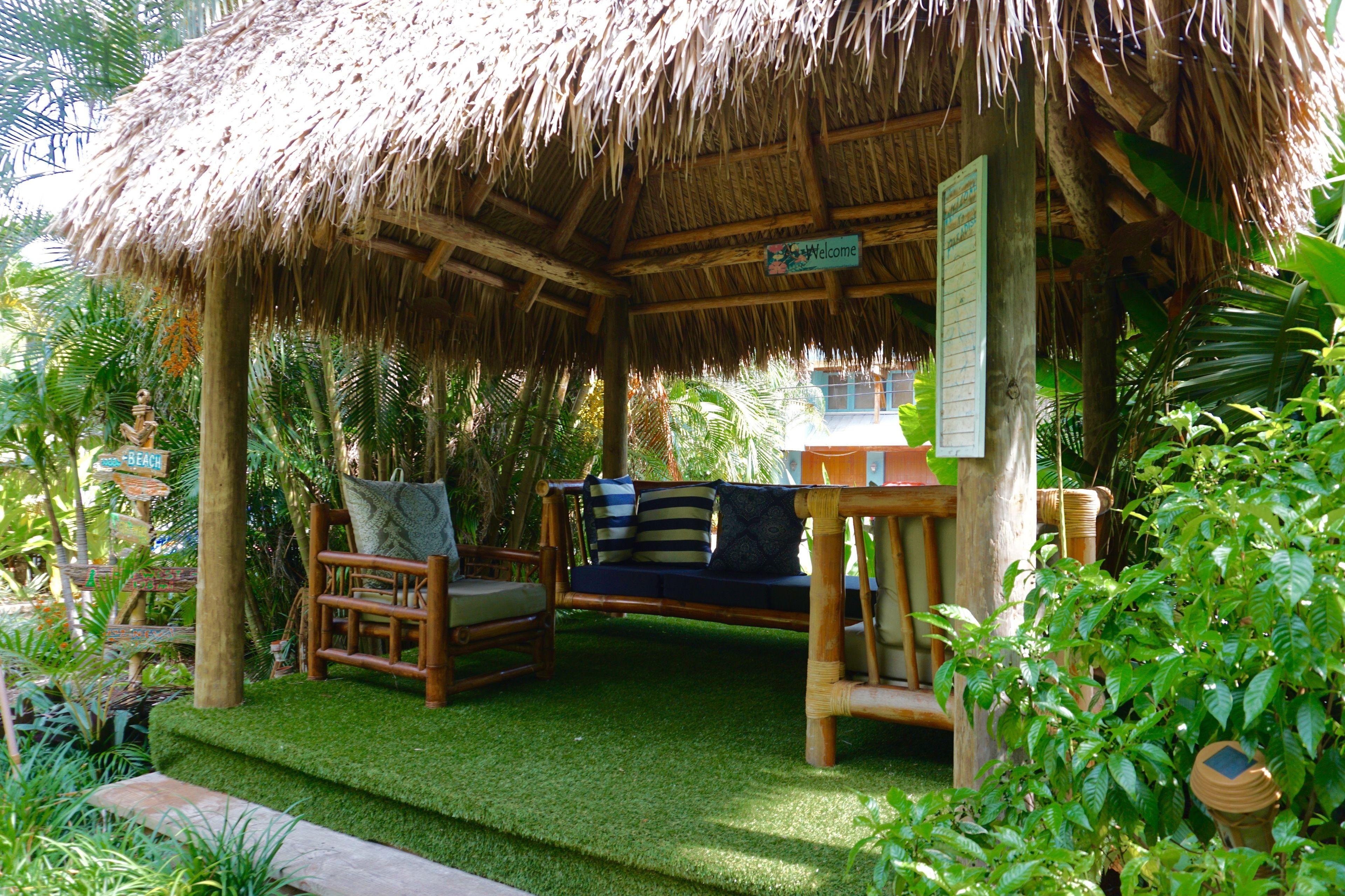 A thatched-roof hut with a wooden bench and a sign reading "Welcome".