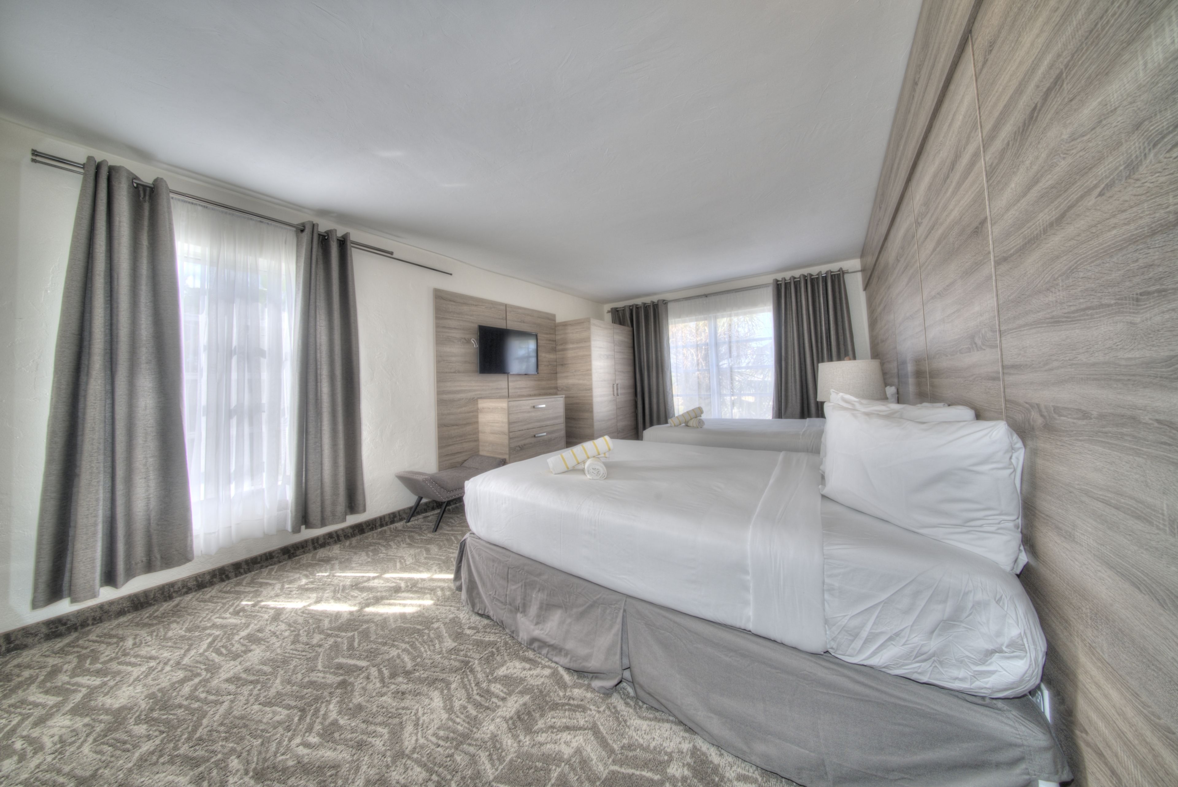 A hotel room with a large bed, a flat-screen TV mounted on the wall, a desk, and a chair.