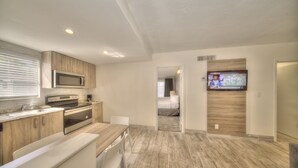 A modern kitchen with wooden cabinets, stainless steel appliances, and a dining area. - Riverside by the Beach Apartments (Pompano Beach)