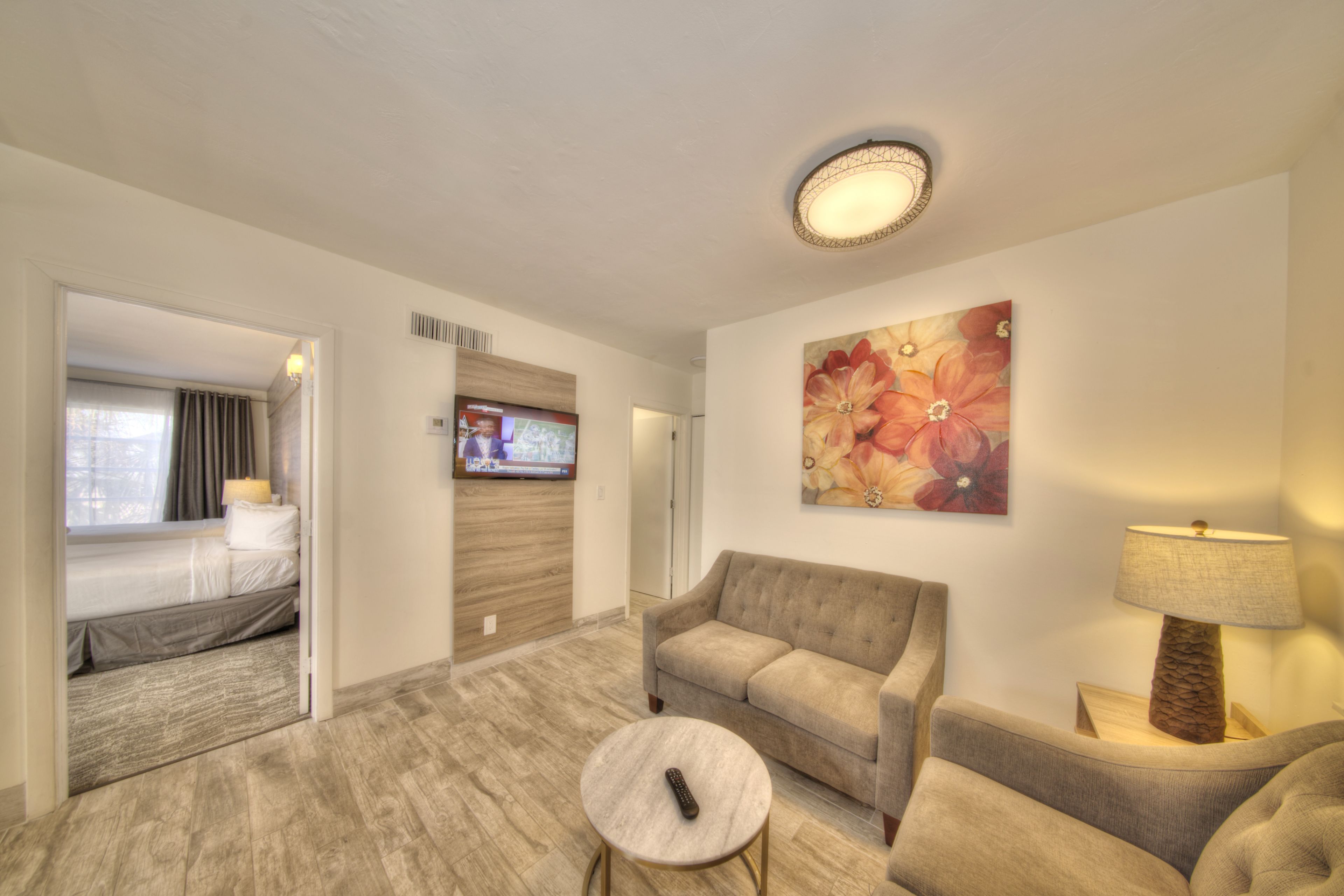 A hotel room with a sofa, a small round table, a TV, and a painting on the wall.
