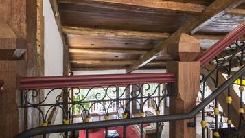 Una escalera de madera con barandilla de hierro forjado, que conduce a una habitación con una silla roja y una mesa.