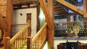 Una escalera de madera con barandilla, un escritorio con sillas y un piso con diseño.